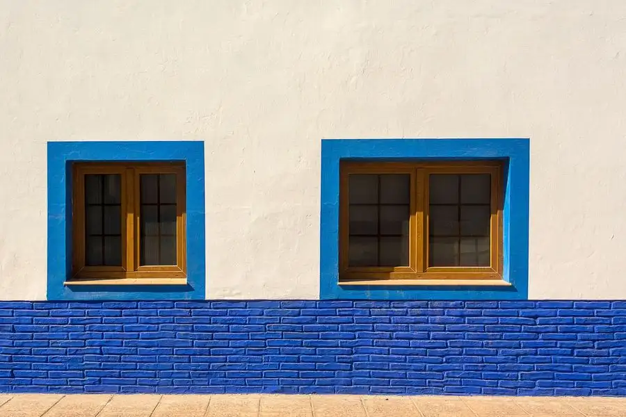 White rendered wall with blue-framed windows
